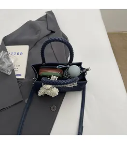 Detail view of navy blue square bag with woven handle showing interior storage capacity