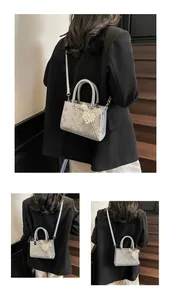 Detail of silver snake skin texture bag with a pearl bow charm and braided handle
