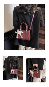 Detail of vintage burgundy crossbody bag with woven handles and pearl bow charm