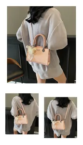 Detail of pink faux-snakeskin handbag with braided handle and pearl lace charm