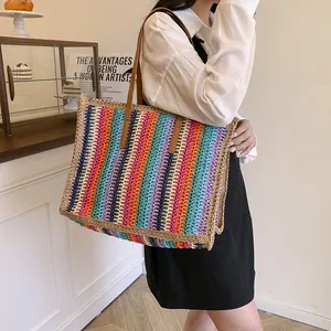 Rainbow striped straw tote bag with brown leather straps shown in a lifestyle setting