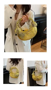 Detail of a shiny gold crescent handbag with metallic texture and removable chain strap