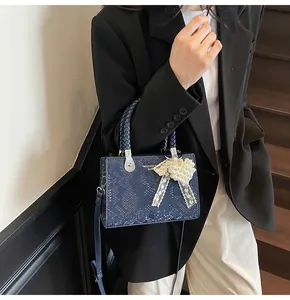 Detail of navy snake print handbag with braided handle and heart pearl charm