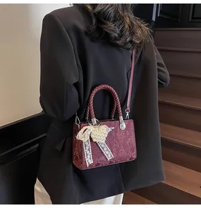 Detail of burgundy snakeskin texture bag with pearl bow accent and lace heart