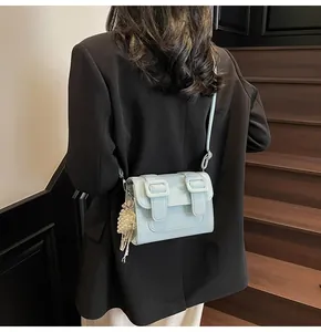 Detail of light blue crossbody satchel with leather texture and pearl grape charm