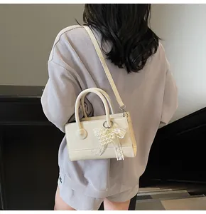 Detail of cream PU leather handbag with pearl bow pendant and adjustable strap