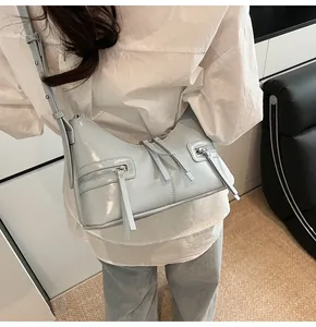 Dettaglio della borsa hobo celeste in pelle lucida con doppie cerniere decorative