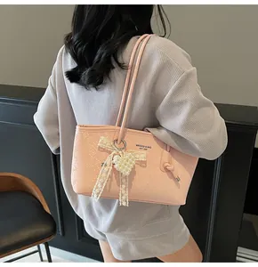 Detail of pink faux snakeskin handbag with lace bow and pearl heart charm