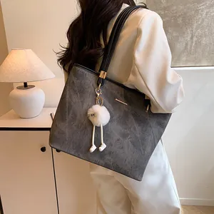 Large gray suede tote bag with black straps and white plush charm on model