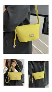 Détail du sac seau jaune en cuir avec logo argenté et pendentif en forme de cœur