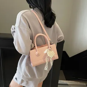 Pink PU leather crossbody bag with pearl heart pendant shown on model in a staircase
