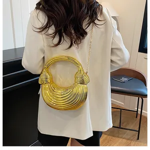 Detail of gold half-moon bag with metallic pleated texture and round handle on white blazer