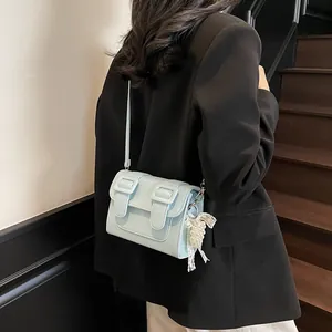Light blue faux leather satchel with pearl pendant on a model in a blazer and white pants
