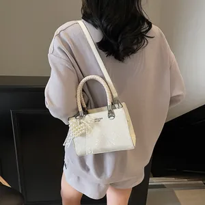White textured leather crossbody bag with woven handle and pearl charm pendant