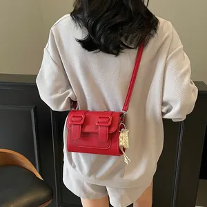 Chic red lychee leather crossbody satchel with pearl pendant and twin buckles for women
