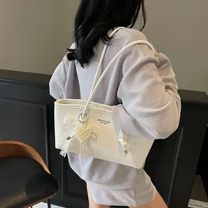 White stylish shoulder tote bag with pearl heart charm and lace bow on a model's shoulder