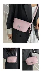 Détail du sac bandoulière rose en cuir grainé avec breloque argentée et logo métal
