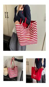 Macro view of oversized striped canvas tote bag with red handles and interior details