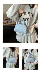 Detail of light blue quilted Boston bag with smooth texture and detachable strap