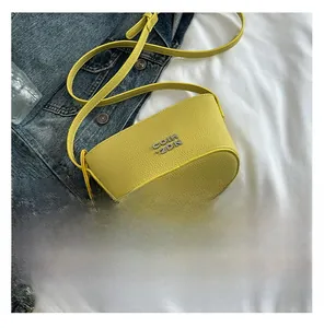 Sac seau jaune en cuir grainé avec logo métallique à côté d'un smartphone noir