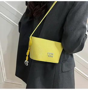 Détail du sac bandoulière en cuir jaune grainé avec logo COIH argenté sur veste grise