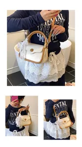 Detail of white litchi pattern square bag with brown handles and a lace bow charm