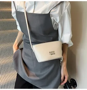 Détail du sac bandoulière blanc texture litchi avec logo métallique COIH argenté