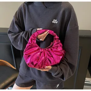 Dettaglio della borsa hobo rosso rosa metallizzato con pieghe su abito grigio