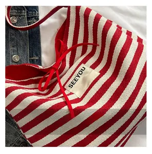 Detail of red and white striped canvas tote bag with SEEYOU label and red bow decoration