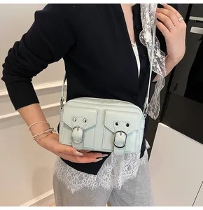 Dettaglio della borsa a tracolla verde menta con tasche multiple indossata dal modello