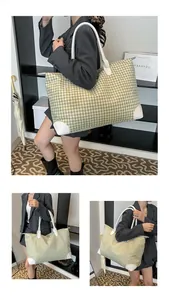 Detail of green houndstooth travel bag showing white leather handles and reinforced corners