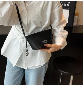 Détail du sac bandoulière noir en cuir grainé avec pendentif coeur argenté et lettrage chic