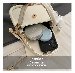 Detail showing internal capacity of the off-white lychee texture crossbody bag with accessories