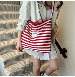 Detail of red and white striped canvas tote bag with 'SEEYOU' patch and drawstring detail
