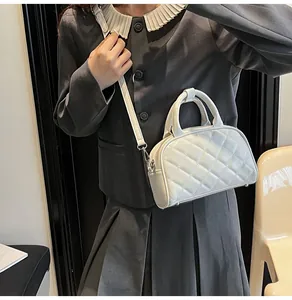Close-up of quilted white Boston bag with round handle and detachable shoulder strap