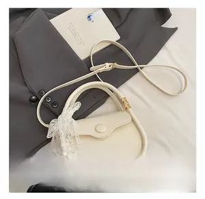 Detail showing creamy white crocodile texture bag with scalloped flap and lace bow