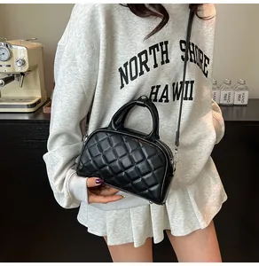 Detail of black quilted boston bag featuring sturdy top handle and glossy faux leather