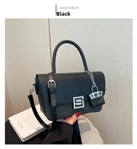 Detail of black vintage shoulder bag with silver geometric lock and mini charm accessory