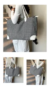 Detailed view of large houndstooth travel bag with white leather straps and zip closure