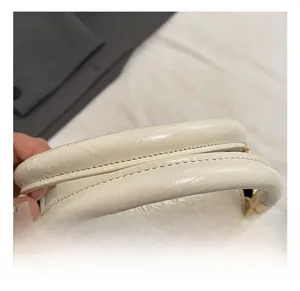 Close-up of creamy white lychee grain leather handbag with golden metal hardware
