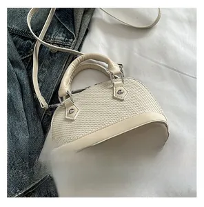 Detail view of woven cream shell bag showing texture, smooth leather trim and silver hardware