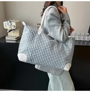 Macro detail of houndstooth weave fabric and white leather trim on large tote bag