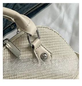Close-up of beige woven seashell bag featuring leather trim and silver metal hardware