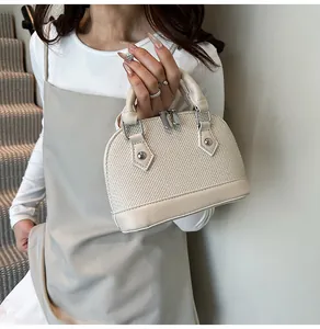 Detail showing woven texture and smooth leather trim on a cream vintage shell handbag