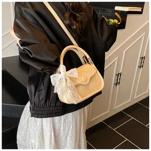 Detail of beige embossed handbag featuring a delicate white lace bow and gold hardware