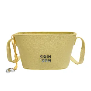 Sac seau minimaliste jaune clair avec pendentif coeur argenté et bandoulière cuir