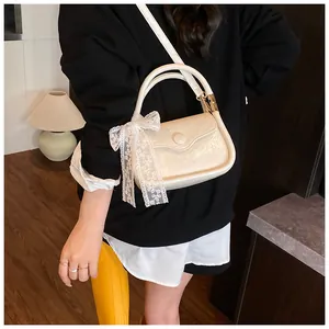 Close-up of cream white pleated faux leather handbag with lace bow and round decorative buckle