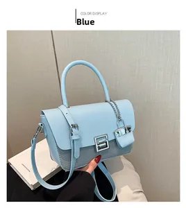 Detail of light blue shoulder bag featuring textured fabric and silver chain charm