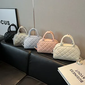 Quilted Boston handbags in black, silver, pink, blue, and white colors on a leather sofa