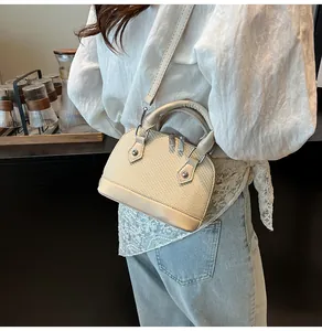Detailed view of beige straw shell bag with leather trim and adjustable crossbody strap